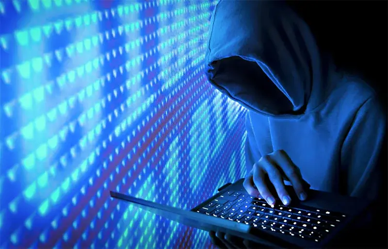 Why hackers target small businesses - cybercriminal using a laptop to exploit weak cybersecurity systems